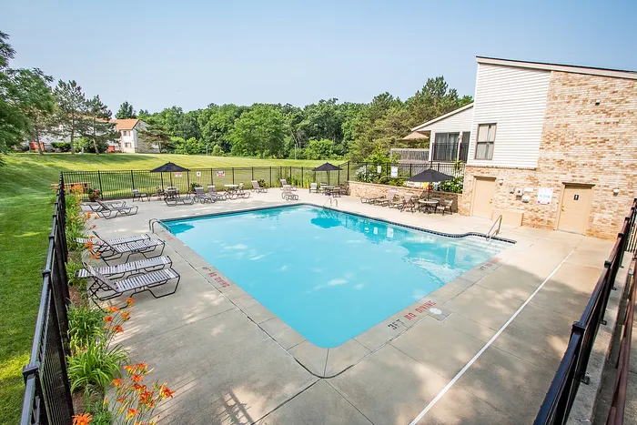 Inviting outdoor swimming pool with relaxing lounge chairs and scenic green surroundings.