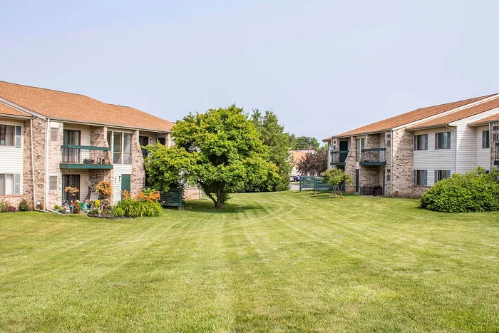 Charming apartment complex with beautifully manicured lawns, inviting balconies, and lush greenery, offering a serene living environment.