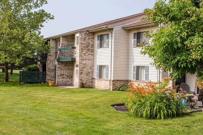 Charming apartment building with lush green lawns, vibrant flower beds, and cozy private balconies.