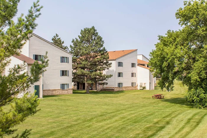 Charming apartment complex surrounded by lush green lawns and mature trees, offering a serene and inviting living environment.