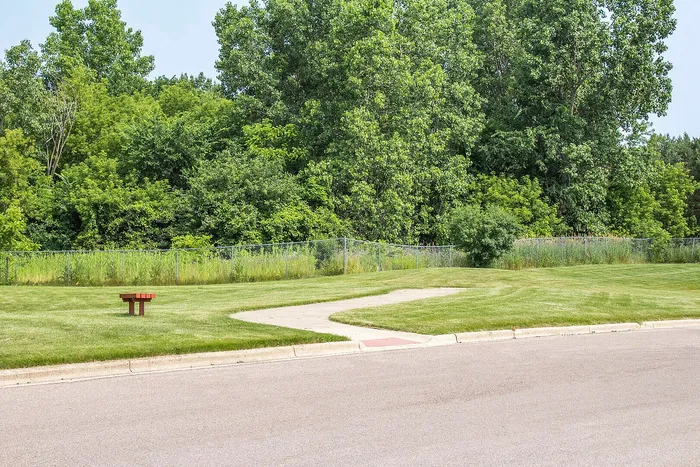 Scenic outdoor area with lush greenery, a serene walking path, and a quaint park bench, offering a peaceful retreat.