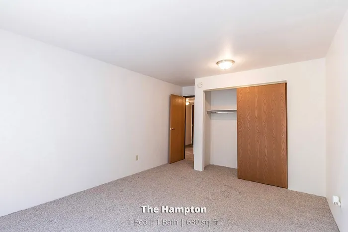 Inviting bedroom in The Hampton apartment featuring a spacious closet and elegant lighting, perfect for creating a cozy sanctuary. 1 Bed, 1 Bath, 630 sq. ft.