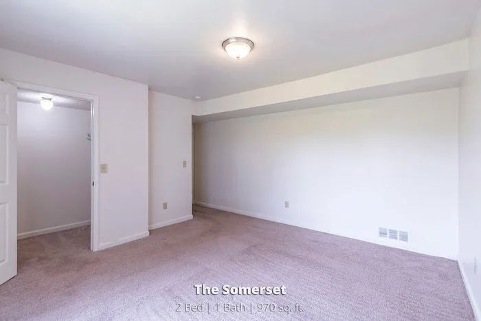 Spacious bedroom in The Somerset apartment, featuring plush carpet and ample natural light, perfect for comfort in a 2-bed, 1-bath, 970 sq ft layout.