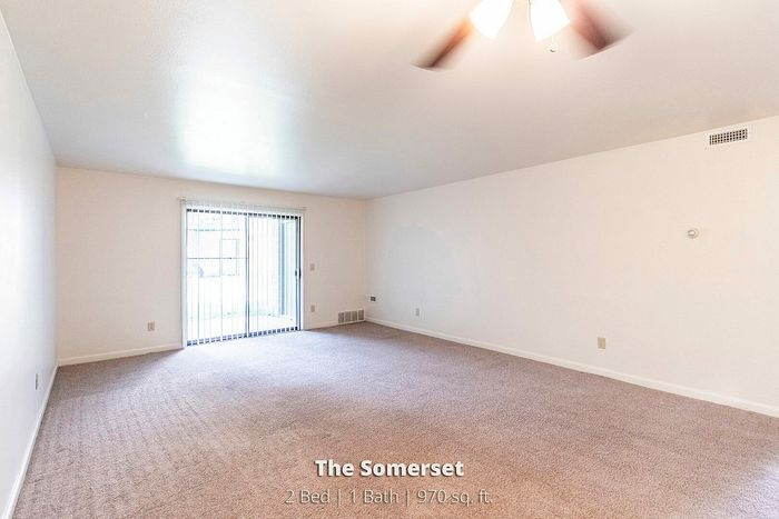 Bright living room with plush carpeting and large sliding glass doors in The Somerset, 2 Bed, 1 Bath, 970 sq. ft.