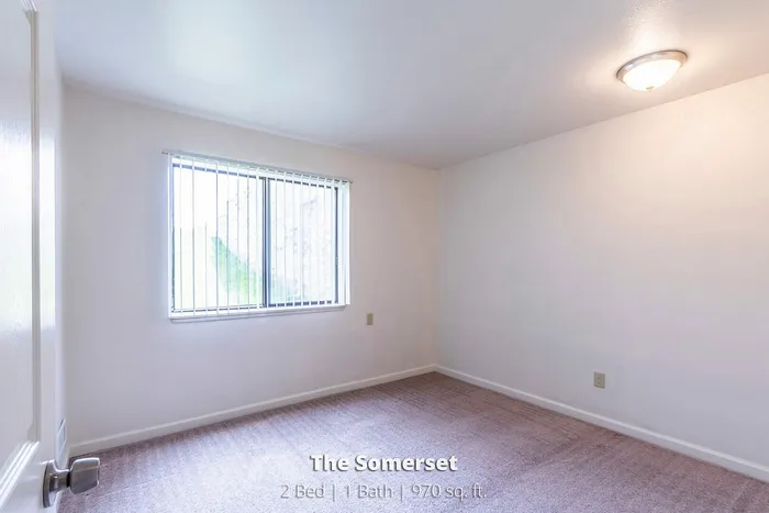 Bright and inviting bedroom in The Somerset apartment, featuring soft carpeting and ample natural light, perfect for relaxation. 2 Bed, 1 Bath, 970 sq ft.