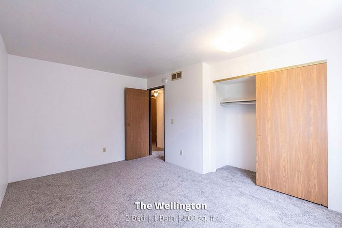 Bright and airy bedroom with plush carpet and ample closet space in The Wellington, a 900 sq ft, 2 bed 1 bath apartment.