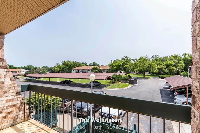 Charming balcony view from The Wellington, overlooking lush greenery and convenient covered parking in a serene area.