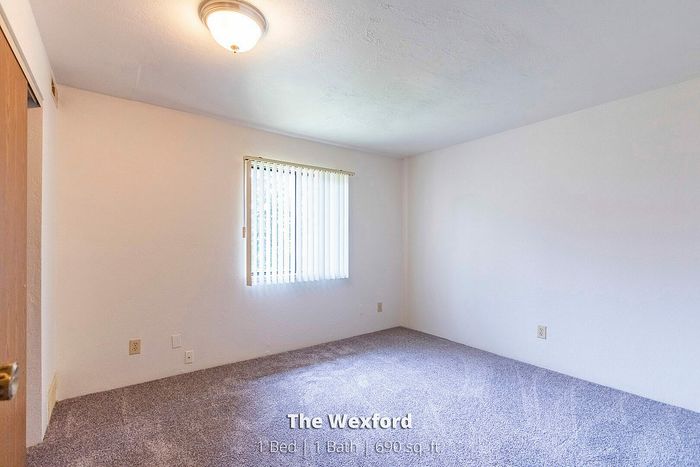 Bright and cozy bedroom in The Wexford apartment featuring plush carpeting and natural light, perfect for relaxation. 1 Bed, 1 Bath, 690 sq ft.