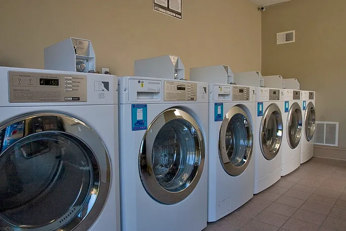 Modern apartment laundry room featuring a row of sleek, efficient washing machines ready for use.