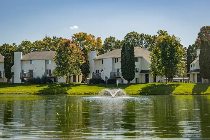 Charming apartment complex with serene pond views, lush greenery, and a refreshing fountain.