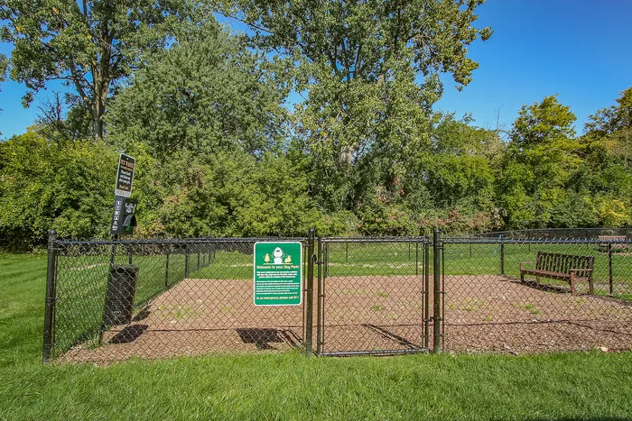 Inviting dog park with lush greenery, a secure fenced area, and comfortable seating for pet owners.