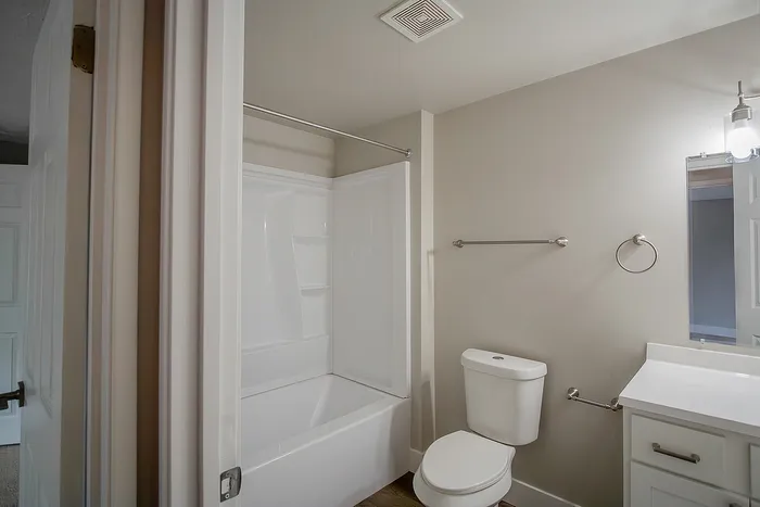 Bright and modern bathroom with sleek white fixtures, a full bathtub, and elegant lighting.