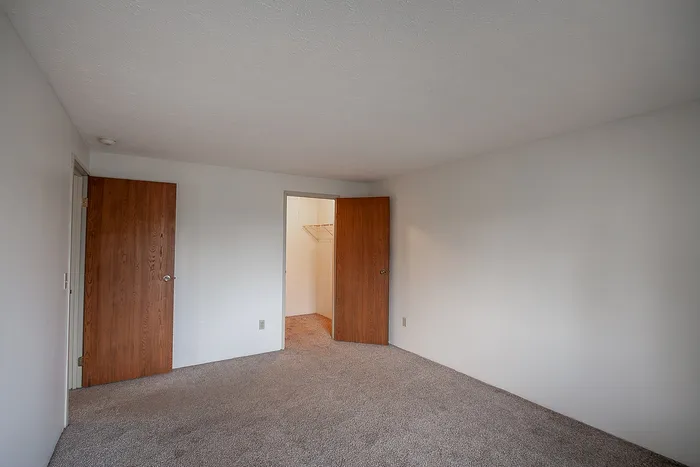 Bright, spacious bedroom with plush carpet and a walk-in closet, perfect for a cozy retreat.