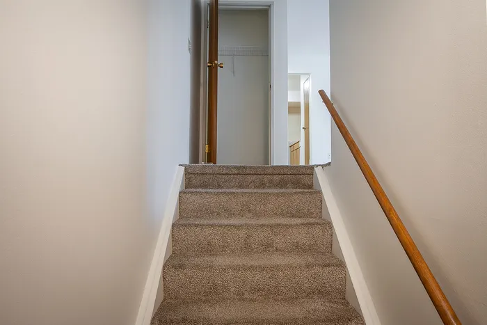 Inviting staircase with soft carpeting leading to a bright and spacious upper floor, perfect for creating a cozy home atmosphere.