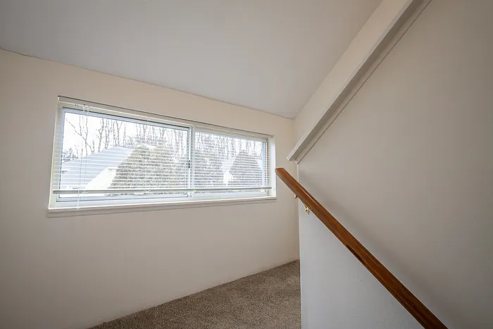 Bright and inviting stairway landing with a large window offering a scenic outdoor view.