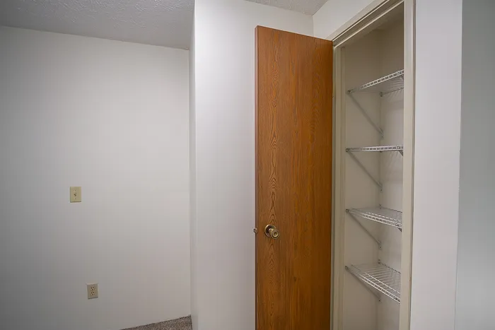 Charming apartment interior featuring a wooden door leading to a spacious closet with wire shelving.
