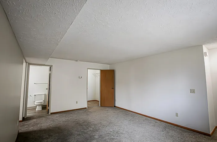 Bright and spacious room with fresh neutral walls, plush carpet, and an inviting design perfect for customization.
