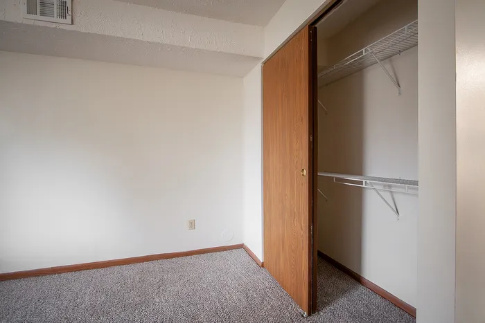 Inviting bedroom space with plush carpet and ample closet storage, perfect for a cozy and organized living experience.