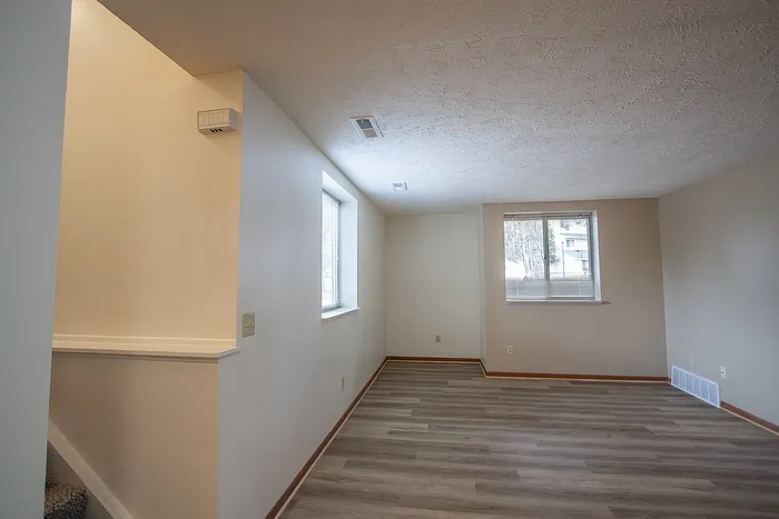 Bright and inviting living space with modern flooring, large windows, and neutral walls, perfect for cozy gatherings.