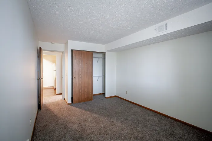 Bright and spacious bedroom with plush carpet, large closet, and modern finishes, perfect for comfort and style.
