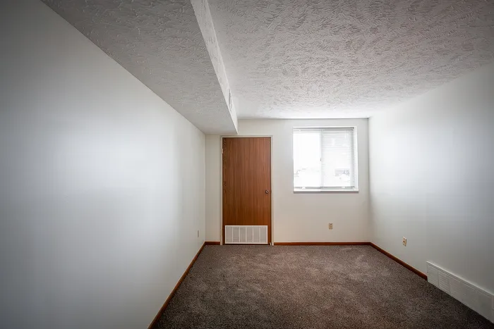 Inviting room with plush carpet, natural light from a large window, and clean, modern finishes.