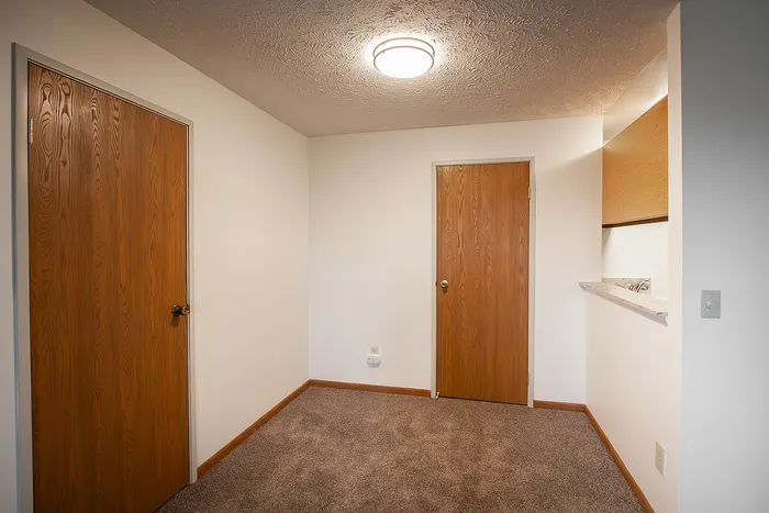 Inviting room with warm wooden doors, plush carpeting, and a convenient breakfast bar.