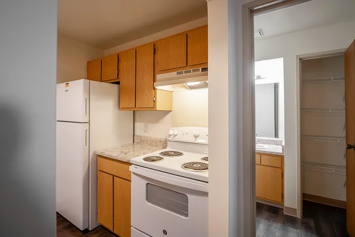 Cozy kitchen with modern wooden cabinets, white appliances, and a sleek marble countertop offering a warm and inviting culinary space.