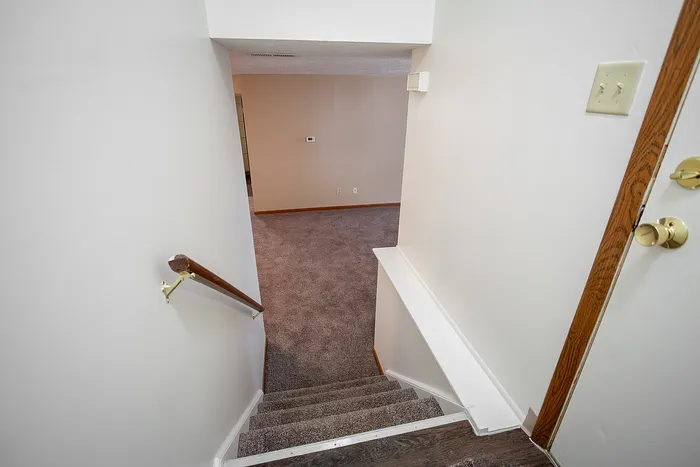Inviting staircase leading to a cozy carpeted room, perfect for family gatherings.