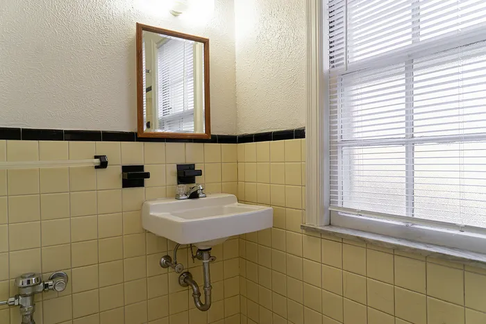 Charming bathroom with vintage yellow tiles, sleek sink, and natural light streaming through the window.