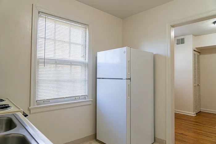 Bright and airy kitchen corner with a modern white refrigerator and sunlit window, offering a warm and inviting atmosphere.