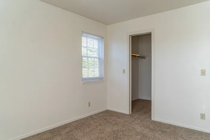 Inviting bedroom with plush carpet, ample natural light, and a convenient walk-in closet.