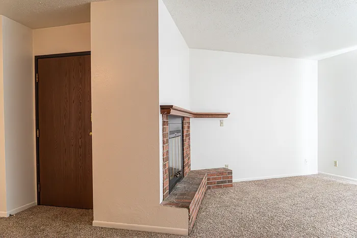 Cozy living space featuring a charming brick fireplace with a wooden mantel, perfect for relaxation and warmth.