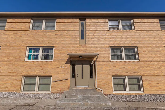 Charming brick apartment building with large windows and inviting entrance set against a clear blue sky.
