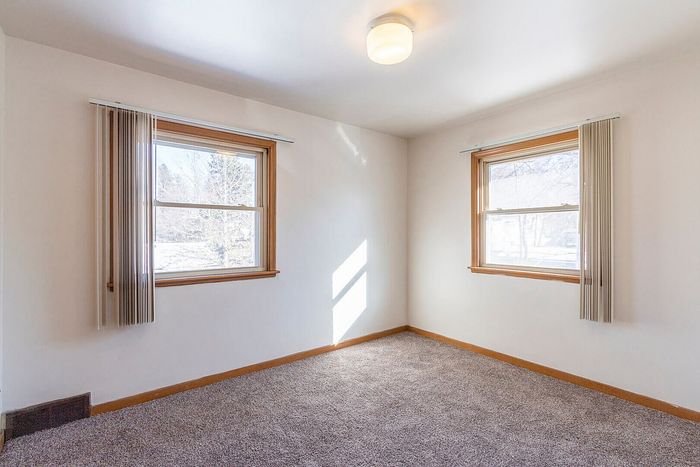 Bright and inviting bedroom with plush carpeting and large windows offering scenic views.