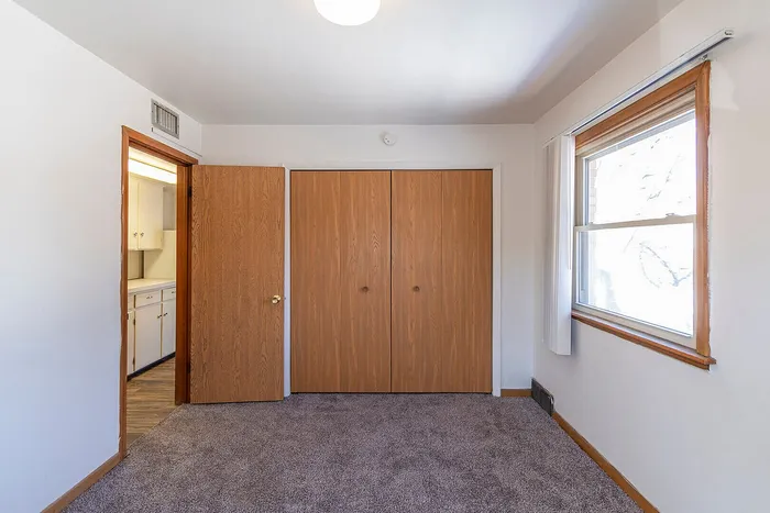 Cozy bedroom with ample natural light, plush carpeting, and expansive closet space.