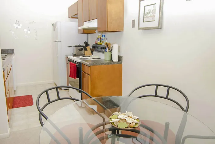 Inviting kitchen with sleek appliances, cozy dining area, and warm wooden cabinetry designed for modern living.