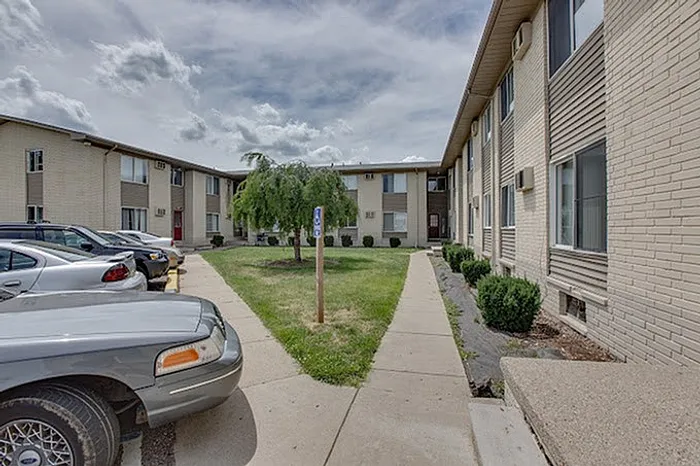Welcoming apartment complex with lush greenery, modern brick facade, and convenient parking.