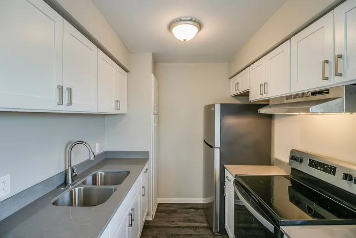 Modern kitchen with sleek stainless steel appliances, elegant white cabinetry, and dark countertops.