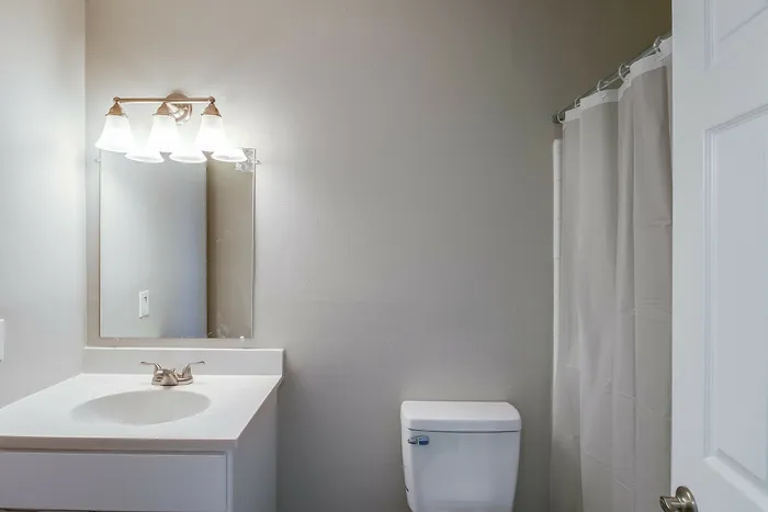 Chic and modern bathroom featuring elegant lighting, sleek white vanity, and a classic shower curtain.