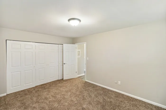 Bright and spacious bedroom with plush carpeting and ample closet space, perfect for comfortable living.