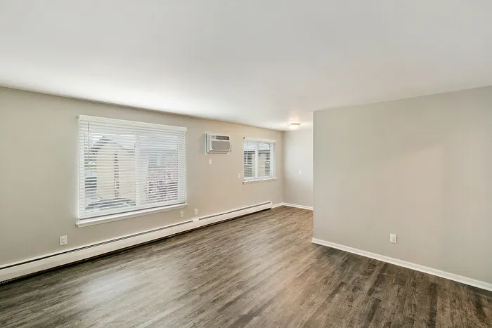 Bright and spacious modern living room with sleek hardwood flooring, large windows, and ample natural light.