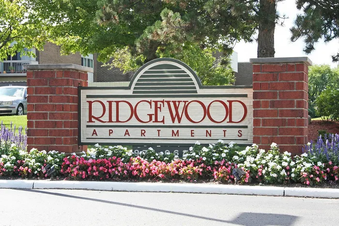 Charming stone entrance sign for Ridgewood Apartments, surrounded by vibrant flowers and lush greenery.
