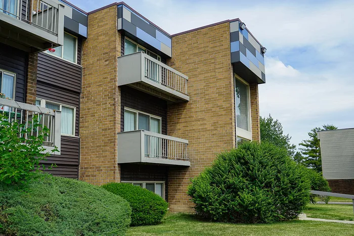 Charming apartment building with modern balconies and lush greenery, offering a serene living environment.