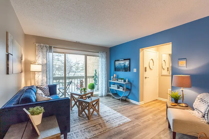 Inviting living room with a cozy blue-themed decor, large window for natural light, and stylish furnishings providing a warm, welcoming atmosphere.