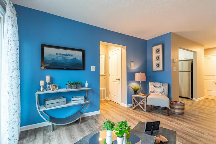 Inviting living space with vibrant blue accent walls, modern decor, and natural light, featuring stylish furniture and a spacious layout.