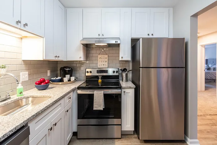 Modern kitchen with sleek stainless steel appliances, elegant granite countertops, and white cabinetry, offering a cozy and efficient space for culinary creativity.