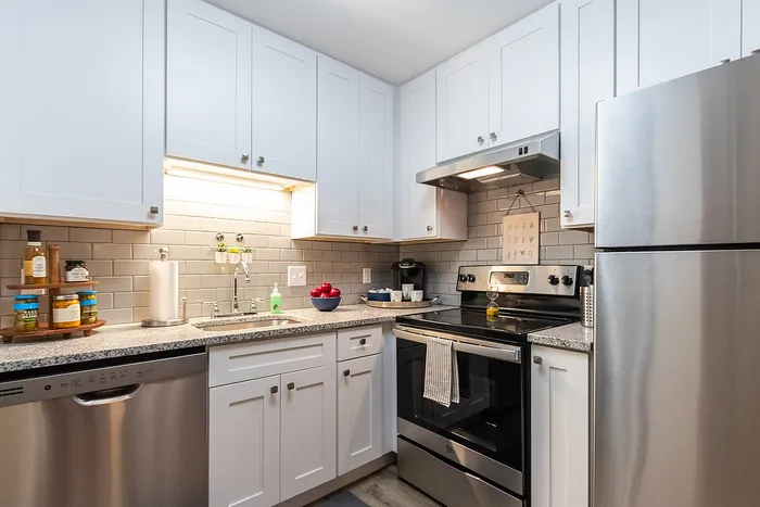 Chic modern kitchen with sleek stainless steel appliances, elegant white cabinets, and a stylish subway tile backsplash.