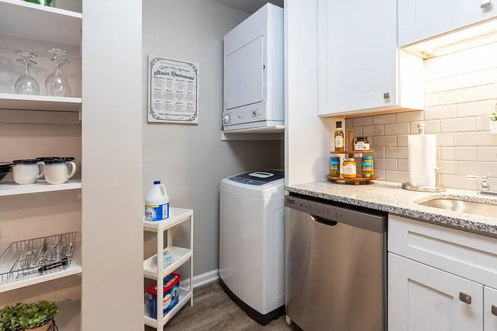 Charming modern kitchen featuring in-unit laundry, stylish shelving, and sleek stainless steel appliances.