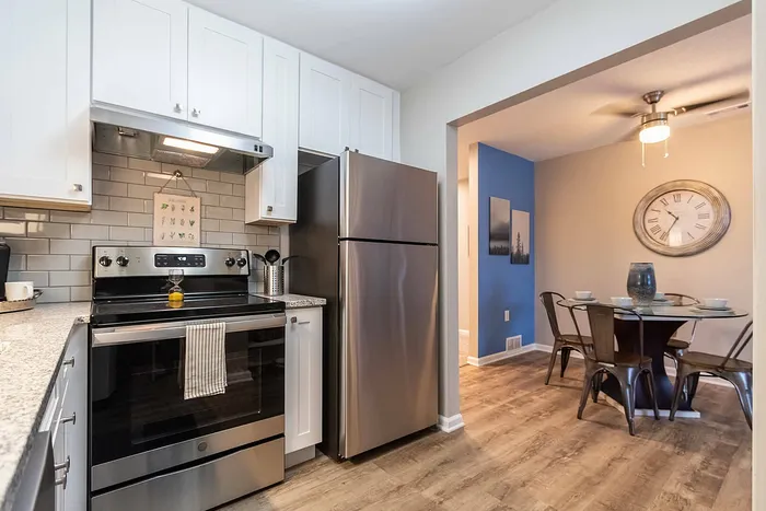 Modern kitchen with sleek stainless steel appliances and charming dining area with a stylish clock accent wall, offering a perfect blend of functionality and elegance.