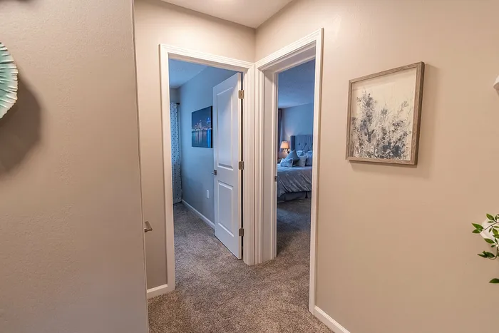 Inviting hallway with plush carpet leads to two elegantly styled bedrooms, creating a warm and welcoming atmosphere.